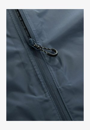 Tamsiai mėlynas vandeniui atsparus džemperis su priekiu užtrauktuku, turintis tekstūruotą audinį ir juodą traukimo kilpelę su mažu kabliuku prisitaikymui.