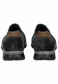 Zapatos de ante negros con un acento de cuero marrón en el talón, que presentan una suela de goma negra texturizada y un diseño suave y aerodinámico.