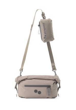 Beige Umhängetasche mit verstellbaren Riemen, vorderer Reißverschlusstasche und kleinem abnehmbarem Beutel mit "pinqponq"-Markenlogo, der am Riemen befestigt ist.
