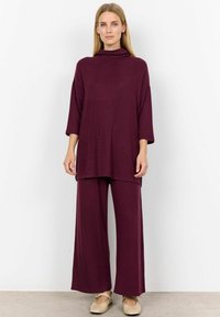 Burgundi loungewear készlet, amely magasan zárt nyakú felsőből és széles szárú nadrágból áll, puha, lélegző anyagból készült.