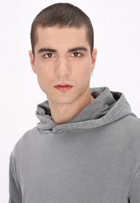 Szürke kapucnis pulóver, texturált anyagból, széles kapucnival, laza szabással és egyszerű dizájnnal. Minimalista és kényelmes megjelenés.