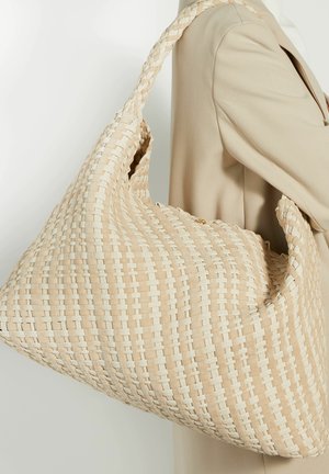 Geweven beige handtas met een slonzige vormgeving, met een gestructureerd oppervlak en een dikke, gevlochten schouderband. Toont een licht en donker geweven patroon.