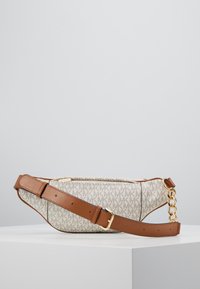 Sac bandoulière en cuir marron avec un tissu beige à motif logo répété, matériel doré et bandoulière réglable.