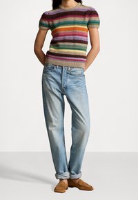 Gestructureerde gebreide top met meerkleurige strepen, korte pofmouwen. Lichtblauwe, relaxte jeans met opgerolde manchetten. Bruine mocassinschoenen.