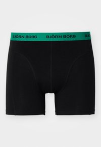 Black boxer shorts made of stretchy material, featuring a green waistband with "BJÖRN BORG" printed in black. Seamless design for comfort.