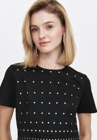 Black short-sleeve dress featuring silver studs in a polka dot pattern, made from soft fabric with a smooth texture.