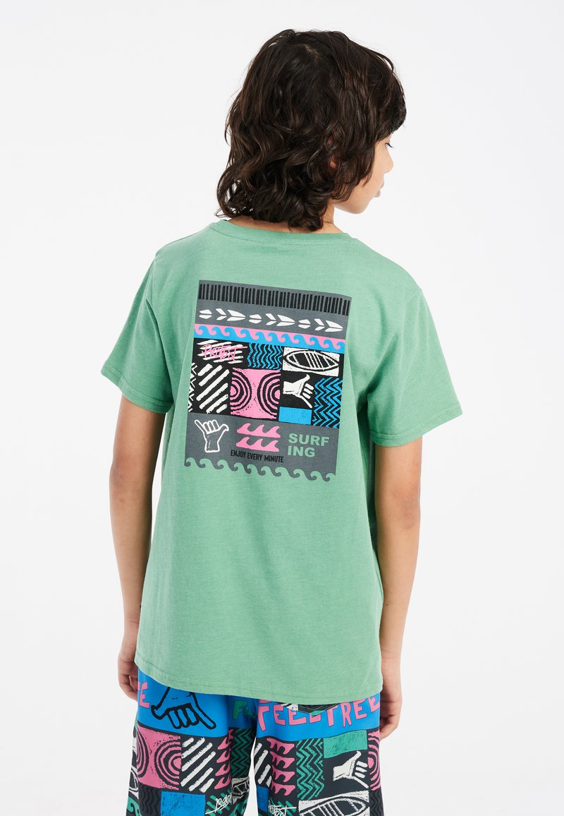 Camiseta verde de manga corta con un gráfico colorido en la parte posterior que presenta patrones inspirados en el surf, texto y diversas texturas.