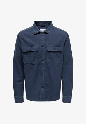 Sötétkék farmering gombos elülső résszel, két mellzsebbe, és hosszú ujjal. Klasszikus gallérral és texturált anyaggal rendelkezik.