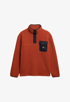 Fleece pullover in verbrande sinaasappel met hoge kraag en marineblauwe knopenlijst. Heeft een grote borstzak met een marineblauwe klep en logo.