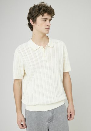 Polo à manches courtes en blanc cassé avec un motif de côtes vertical texturé, patte de boutonnage à trois boutons et ourlet élastiqué.