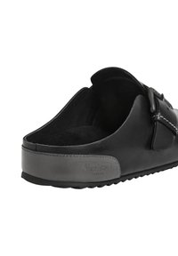 Crne slip-on mule cipele s teksturiranom potplatom, remenom sa kopčom na vrhu, i urezanim natpisom "Pepe Jeans London" sa strane blizu pete.