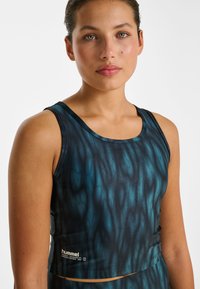 Haut de sport sans manches avec un motif ondulé bleu foncé et noir, fabriqué en tissu léger, doté d'un col en U et d'un logo à l'ourlet.