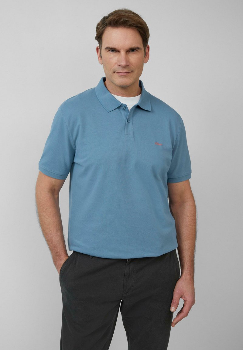 Lichtblauwe polo gemaakt van gestructureerd katoen, met een klassieke kraag en drie knopen, gecombineerd met donkere broek. Opvallend logodetail.