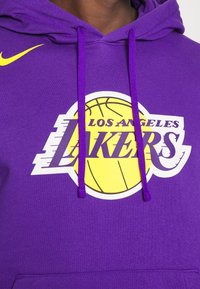 Sweat à capuche violet en coton, avec un graphisme de ballon de basket blanc orné d'accents jaunes et le texte "LOS ANGELES LAKERS" en violet.