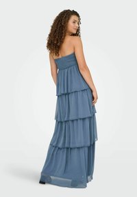 Brezramenska maksi obleka v mehki modri barvi, z večplastnimi sloji lahkotnega šifona za zračno silhueto. Poškodovan detajl bodice.