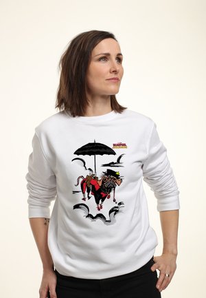 Kvinde iført en hvid sweatshirt med en tegneseriehund klædt som Deadpool, der holder en paraply og svæver blandt skyerne.