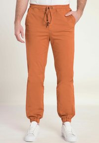Orange joggerbyxor med elastiska muddar och dragsko i midjan, med sidofickor och ett mjukt, lätt tyg.