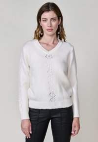 V-Ausschnitt, langärmeliger Pullover aus weich weißem Material; mit einem Rautenspitzenmuster auf der Vorderseite und gerippten Bündchen und Saum.