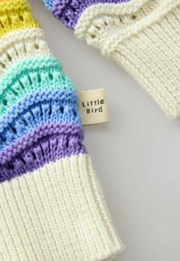 Prodotto lavorato a maglia con una base a coste di colore crema, caratterizzato da strisce multicolori in giallo, verde, blu e viola. L'etichetta riporta 'Little Bird'.