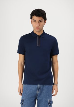 Polo bleu marine avec fermeture éclair et accents rouges, fabriqué en tissu lisse. Manches courtes et design de col classique.