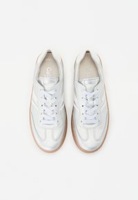 Stříbrné kožené tenisky s perforovaným designem, plochými tkaničkami a gumovou podrážkou. Mají jemné postranní pruhy a polstrovaný límec.