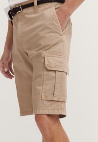 Beige cargo shorts made of lightweight fabric, featuring side pockets and a comfortable fit. Includes a woven brown belt.