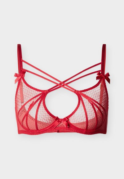 Red lace bra with sheer fabric, crisscrossed straps, and decorative bows at the shoulder. Features a round cutout and soft texture.