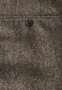 Brown herringbone fabric with a fine texture, featuring a single black button and a top pocket detail.