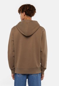 Felpa con cappuccio marrone, dal morbido tessuto, con polsini a costine e tasca a marsupio. Il design presenta una vestibilità comoda e un colore neutro.
