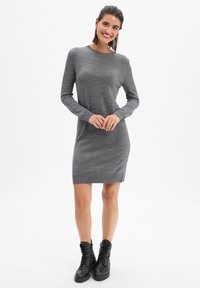 Robe bodycon à manches longues grise avec des poignets et un ourlet côtelés, en tissu tricoté texturé, complétée par des bottes noires à lacets.