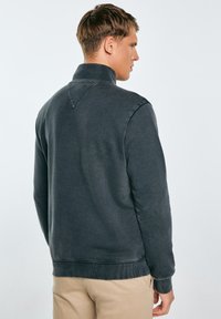 Tumed hall sweatshirt kõrge kraega, ribitud varrukate ja äärisega, mis sisaldab krae taga peent V-kujulist detaili. Sile kangas.