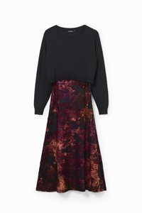 Čierny cropped top s dlhým rukávom, ktorý je vrstvený nad midi šatami s bohatým, tmavofialovým kvetinovým vzorom a kontrastnými zlatými detailmi.