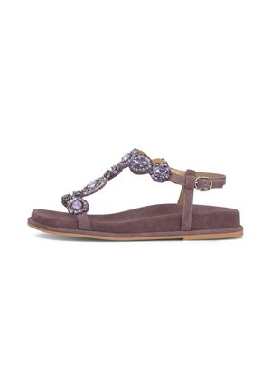 Sandalia plana morada con suela de ante y tiras adornadas con grandes y pequeñas piedras preciosas lavanda, con cierre de hebilla en el tobillo.