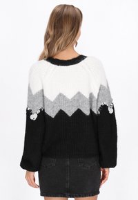 Stickad tröja med ett zickzackmönster i svart, vitt och grått. Långa ärmar med paljettdetaljer, rund halsringning och avslappnad passform.
