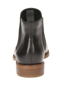 Sort læder ankelstøvle med elastiske sidepaneler, rund tå og en stablet træhælhøj. Glat tekstur, minimalistisk design.