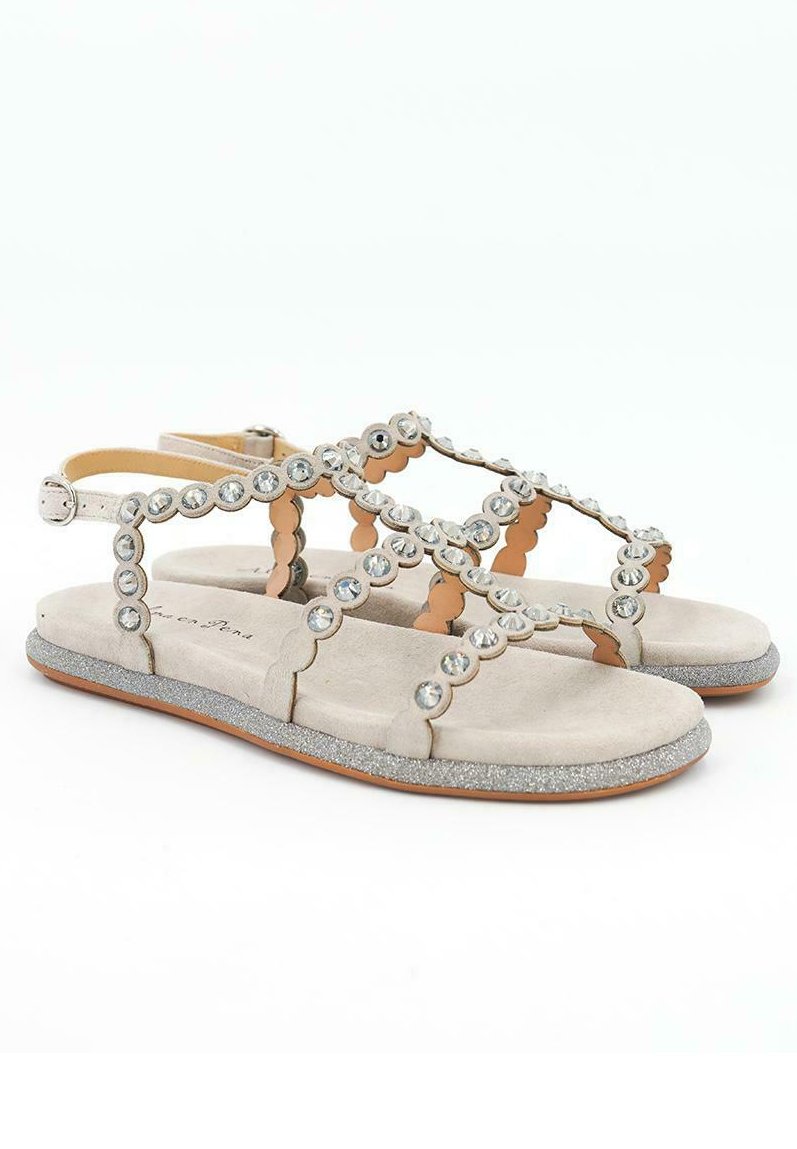 Sandalias de ante gris claro con un diseño en forma de ondulación, adornadas con strass circulares y una suela brillante para un detalle adicional.