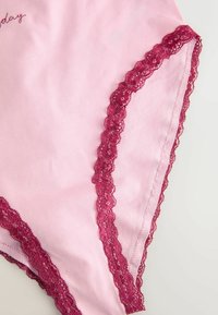 Roosa puuvillane aluspesu, mille servadel on õrn burgundia pitsäär. Sile tekstuur ja tikand, kus on kirjas "täna."