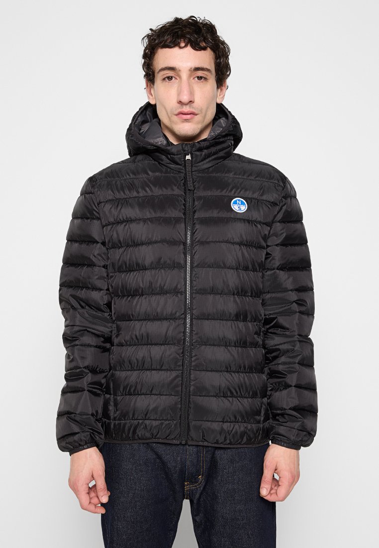 Giacca a vento nera con zip frontale, cappuccio e polsini a costine. Presenta trapuntatura orizzontale e un piccolo logo blu sul lato sinistro del petto.