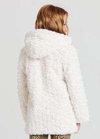 Cappotto in finta pelliccia bianca con un esterno testurizzato e soffice e cappuccio. Il design è di taglio morbido, con maniche lunghe e orlo leggermente arrotondato.