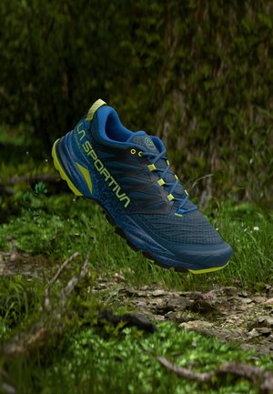 Blue and black athletic shoe with yellow accents, featuring a textured upper, cushioned sole, and a lightweight design for trail running.