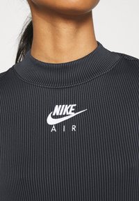 Svart, ribbad topp med hög hals som har en vit broderad Nike-logotyp och "AIR"-text, designad för en åtsittande silhuett.