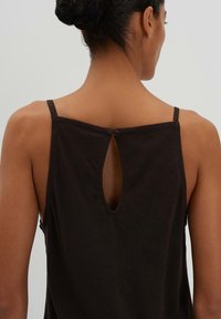 Schwarzes ärmelloses Top mit einem Schlitz am Rücken, dünnen Trägern und einem strukturierten Stoff. Einfaches und figurbetontes Design.
