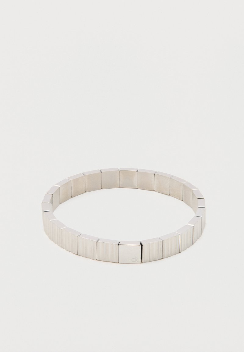 Bratara din argint, alcătuită din înlănțuiri rectangulare din metal, cu o suprafață texturată și margini netede, având un branding subtil.