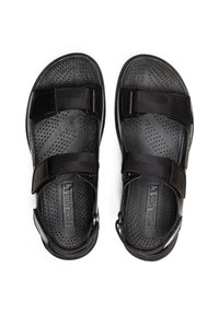 Sandalias negras con suela de goma perforada, correas de tela ajustables y una plantilla texturizada. Logo de la marca visible en las plantillas.