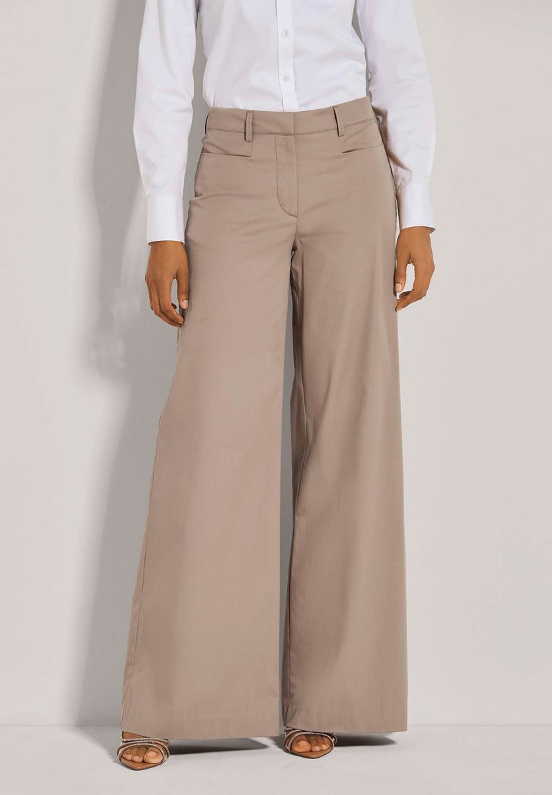 Beige wijde pantalon gemaakt van een gladde stof, met een op maat gemaakte pasvorm, voorzakken en een schone tailleband.