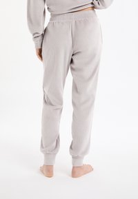 Grijze gebreide pyjamabroek met elastische tailleband en omgeslagen enkels, met een zachte textuur en een ontspannen pasvorm. Geen zichtbare patronen of details.