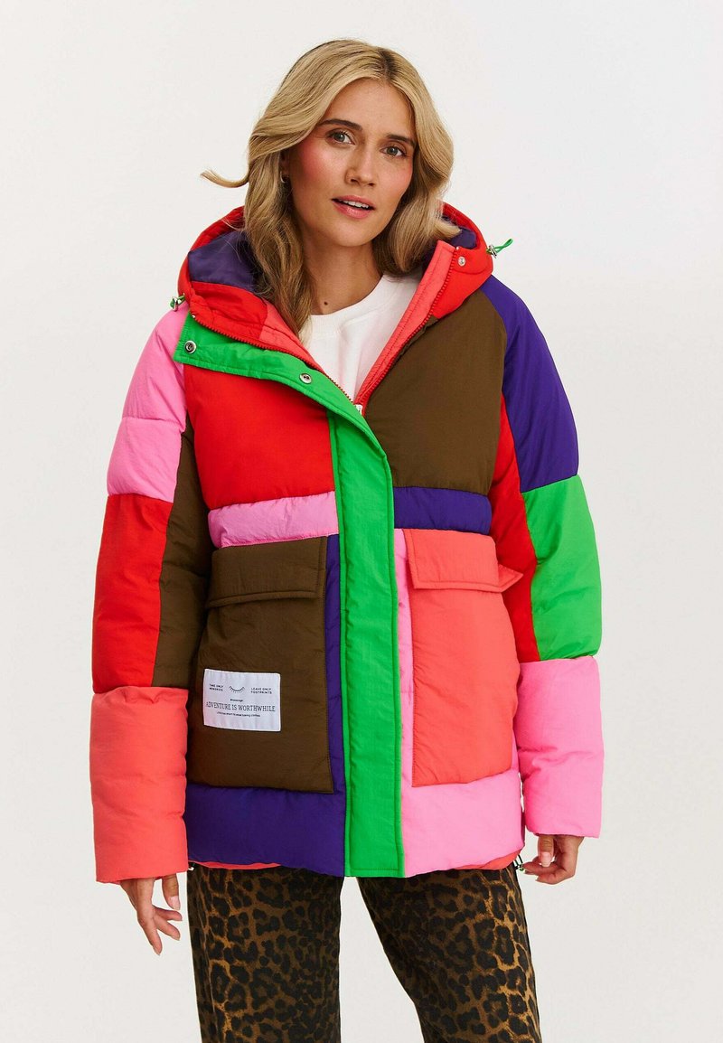 Farebná nafukovacia bunda pozostávajúca z červených, ružových, zelených, hnedých a fialových sekcií, so zipsom vpredu, cvokmi a dvoma prednými vreckami.