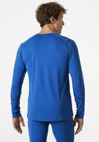 Langarm sportshirt in felblauw, met een textuurstof, zwarte stikaccents en een slimfit vorm met raglanmouwen.