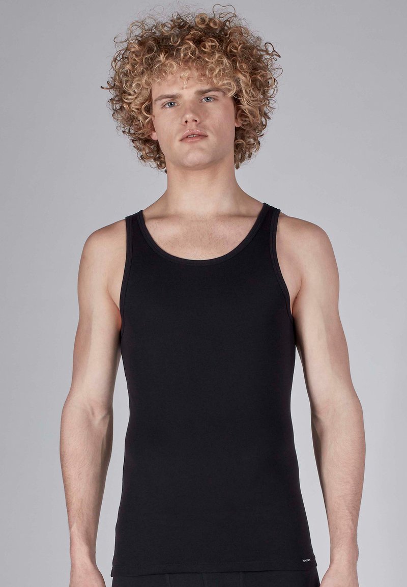 Black cotton tank top with a round neckline, fitted shape, and minimal stitching details. The fabric appears smooth with a simple design.