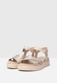 Beige platform sandals with cross-over metallic straps and an adjustable ankle buckle. Soft texture with a thick, sturdy sole.